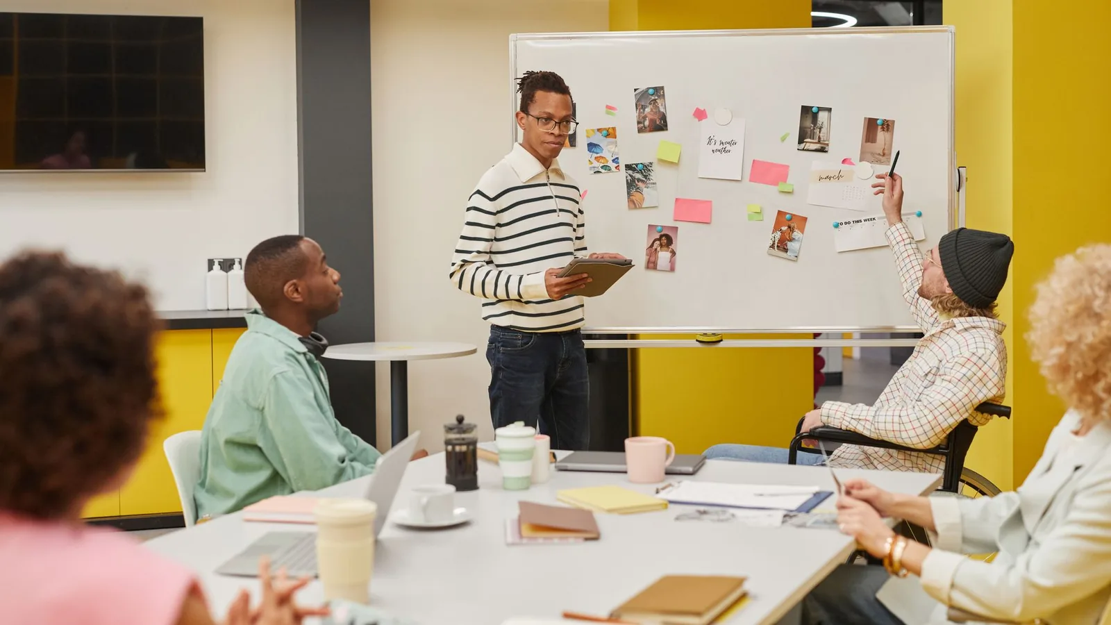 Multi-generational team of employees collaborating around laptops in a modern office workplace