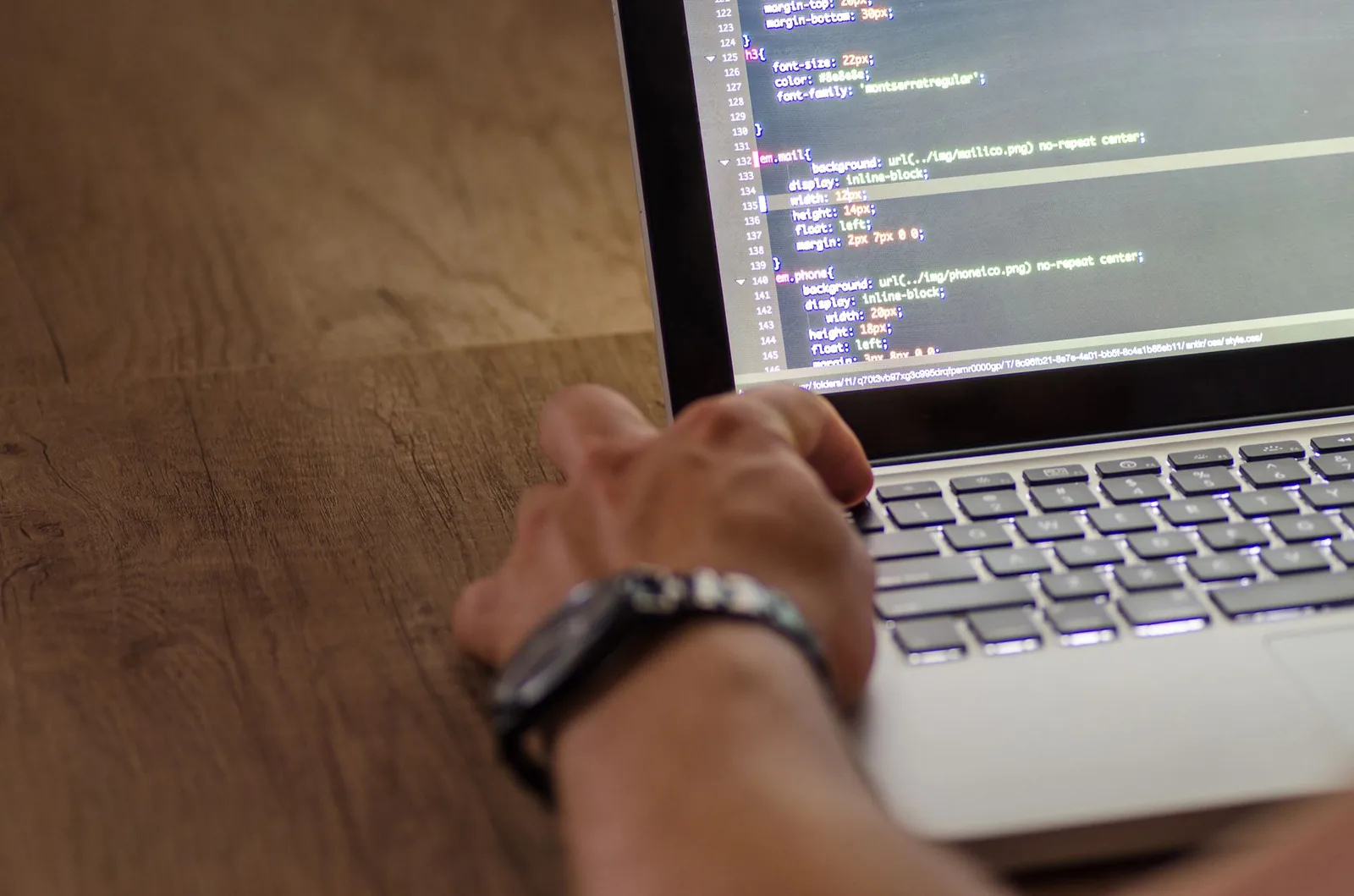 Developer reviewing AI integration workflow code on laptop terminal with dual monitors