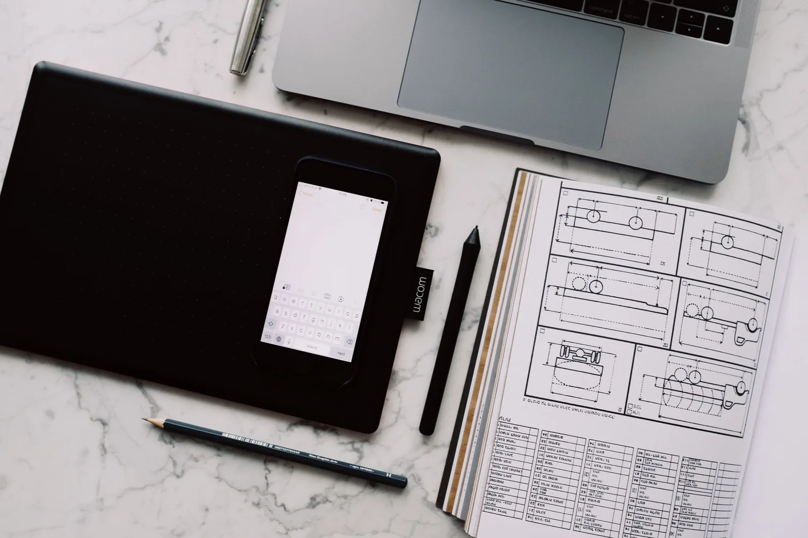 Web designer reviewing website wireframes and pricing budget on laptop with sketches on desk