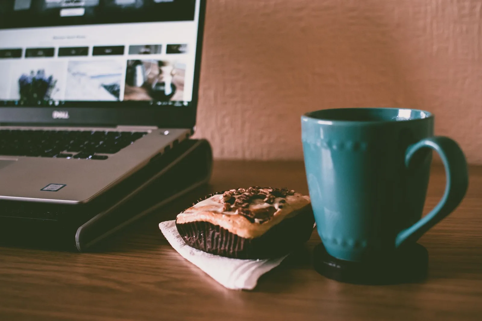 Person building a business website on a laptop at a clean desk workspace with notebook and coffee