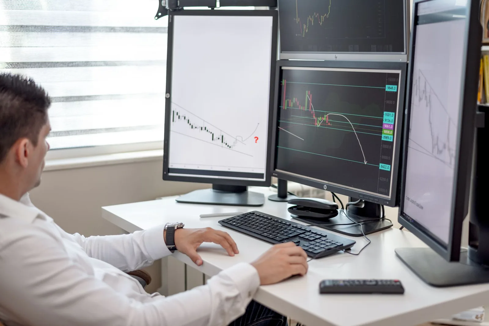 Financial analyst reviewing reconciliation data on multiple monitors at a trading desk