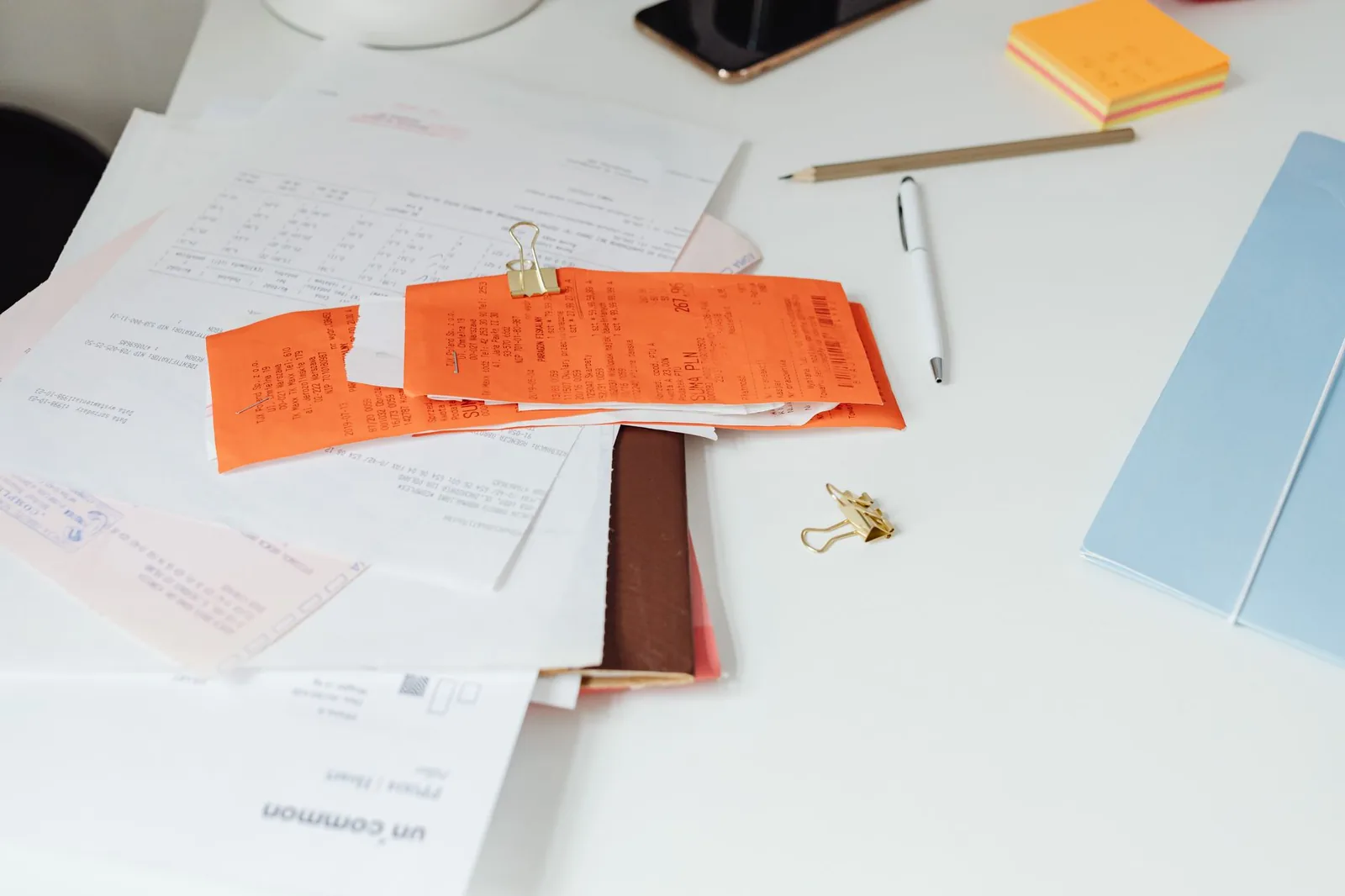 Stack of paper invoices and financial documents on a desk ready for PDF data extraction processing
