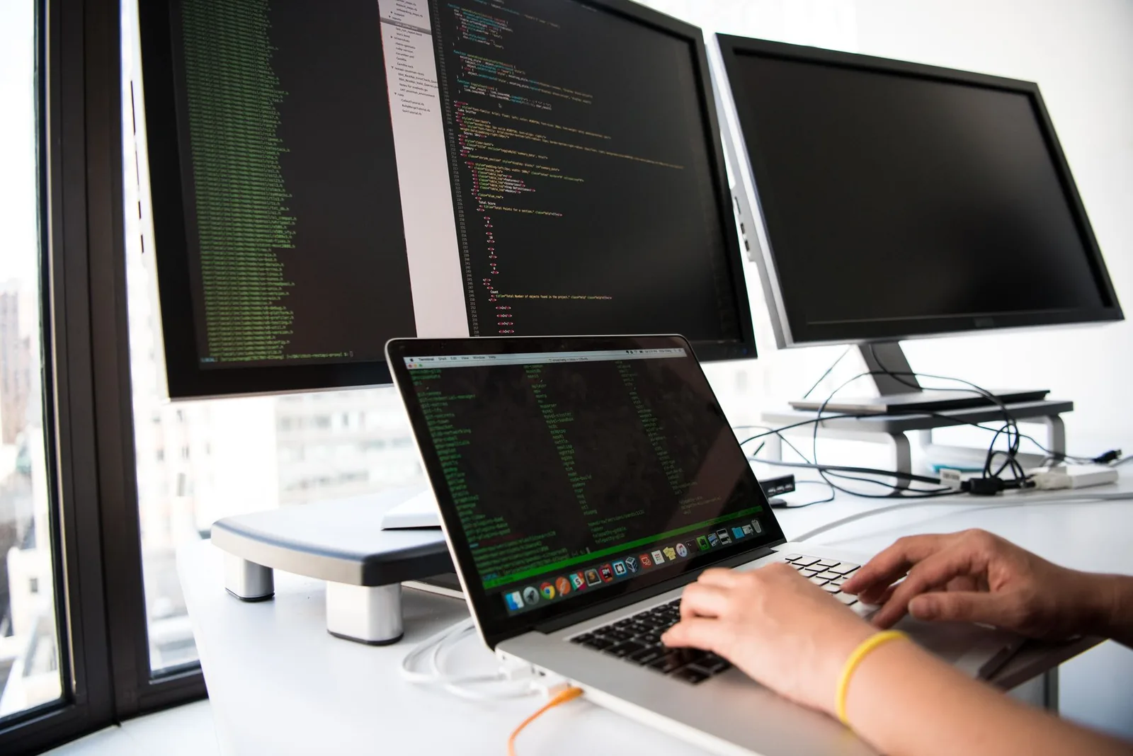 Developer monitoring AI agent logs and eval metrics on multiple screens in a production dashboard