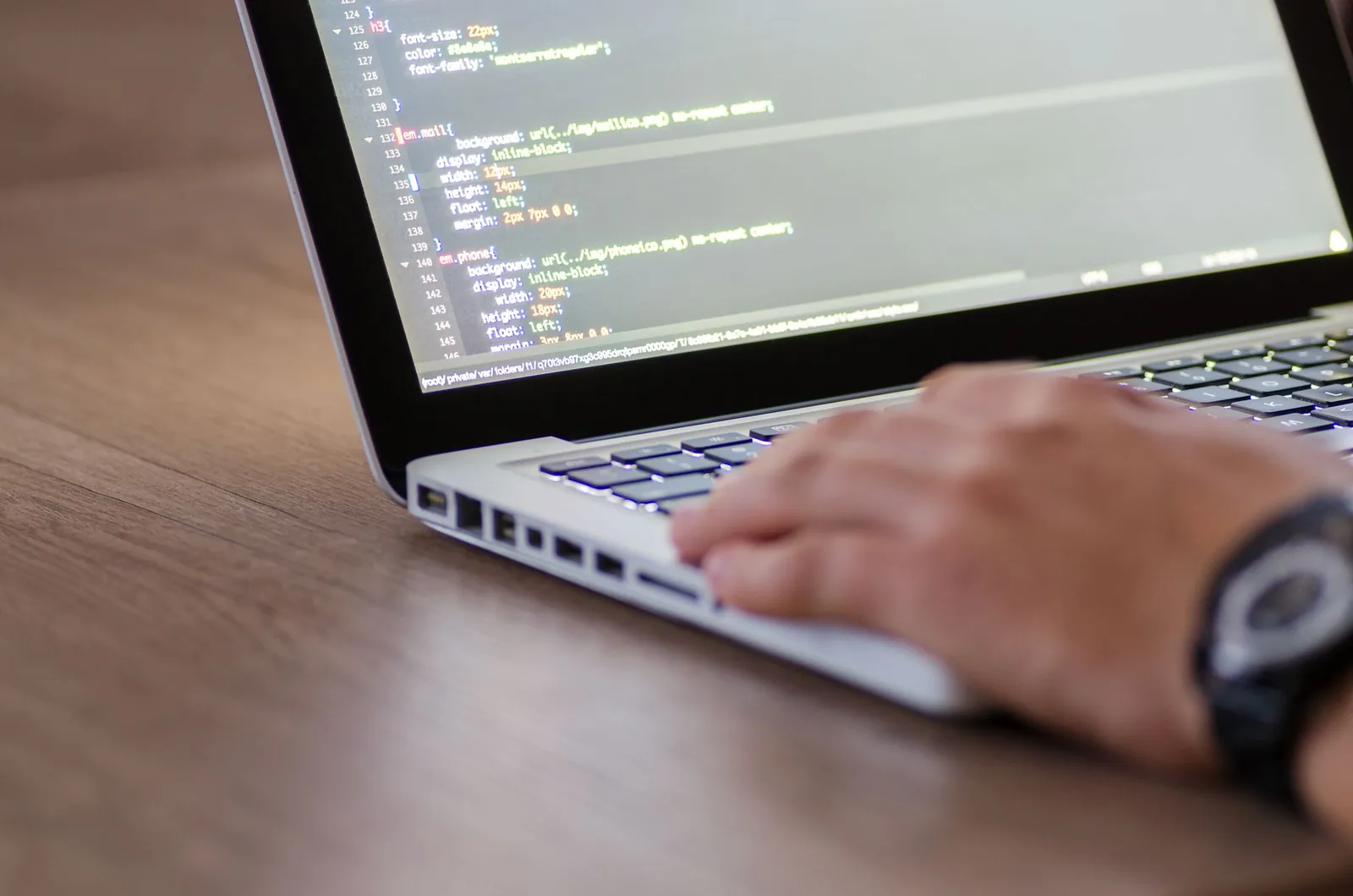 Software developer working on custom bespoke application code on laptop in modern office workspace